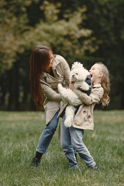 Mutter und ihre Tochter spielen mit Hund. Familie im Herbstpark. Haustier-, Haustier- und Lebensstilkonzept