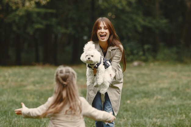 Mutter und ihre Tochter spielen mit Hund. Familie im Herbstpark. Haustier-, Haustier- und Lebensstilkonzept