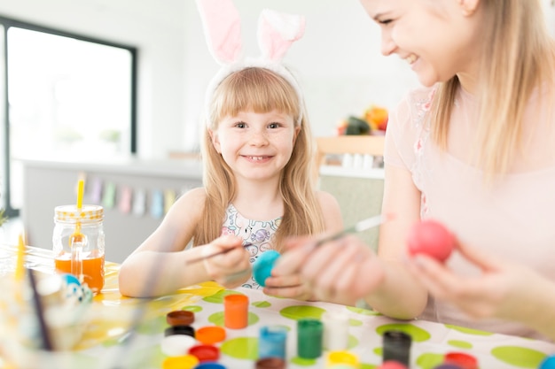 Mutter und Kind, die zusammen Ostereier malen