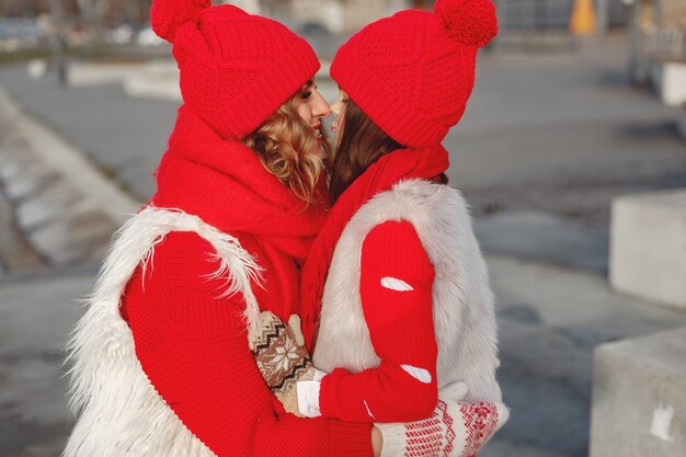 Mutter und Kind in gestrickten Wintermützen in den Familienweihnachtsferien. Handgemachte Wollmütze und Schal für Mama und Kind. Stricken für Kinder. Oberbekleidung stricken. Frau und kleines Mädchen in einem Park.