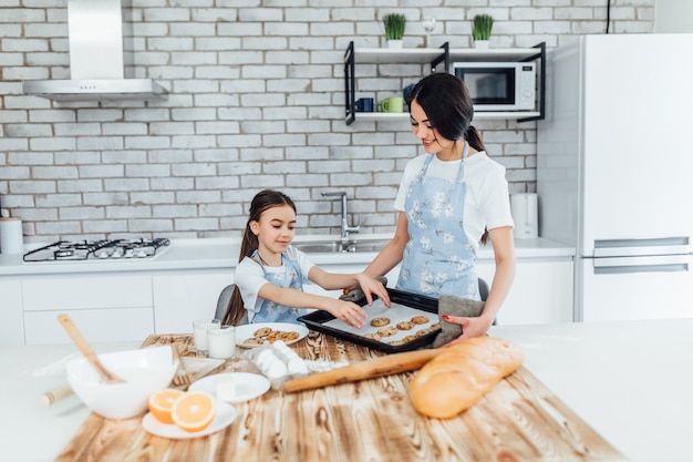 Mutter und Kind kochen gemeinsam Kekse in moderner weißer Küche