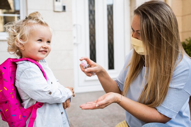 Mutter und Kind mit medizinischen Masken und Händedesinfektionsmittel