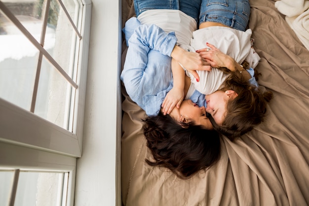 Mutter und kleine Tochter, die auf Bett umarmen