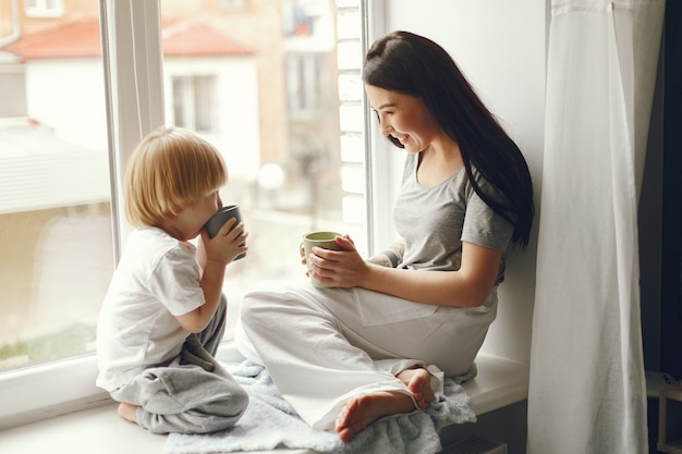 Mutter und kleiner Sohn, die auf einem Fensterbrett mit einem Tee sitzen