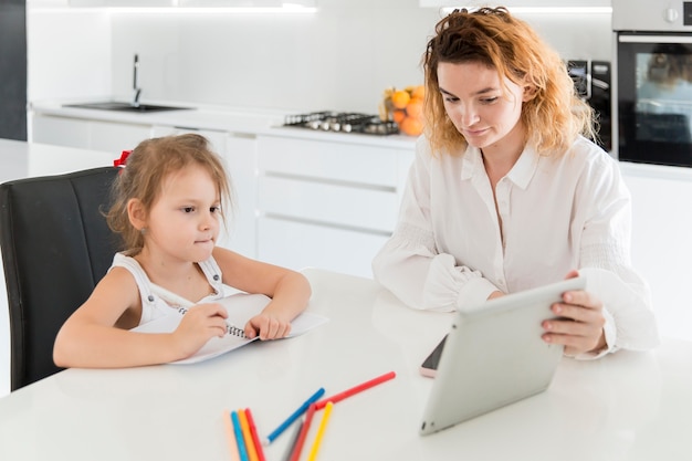 Mutter und Mädchen betrachten Tablette