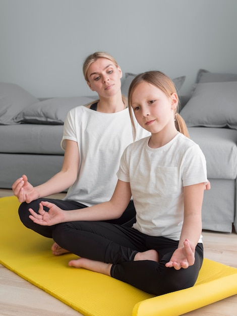 Mutter und Mädchen zu Hause praktizieren Yoga