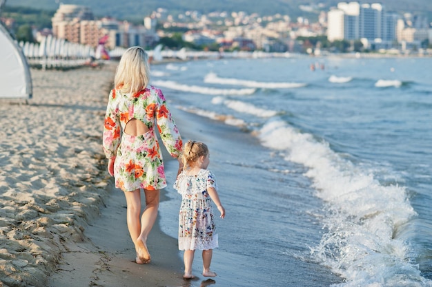 Mutter und schöne Tochter, die Spaß am Strand haben Porträt einer glücklichen Frau mit einem süßen kleinen Mädchen im Urlaub