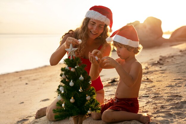 Mutter und Sohn am Strand mit Weihnachtsmützen