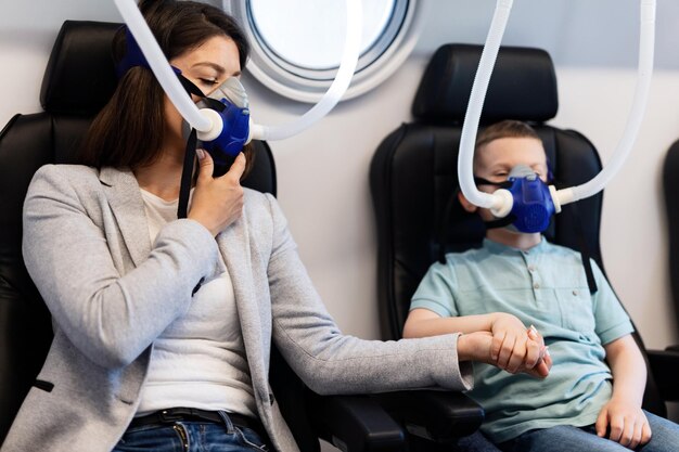 Mutter und Sohn atmen durch Sauerstoffmasken und halten Händchen in der Überdruckkammer in der Klinik