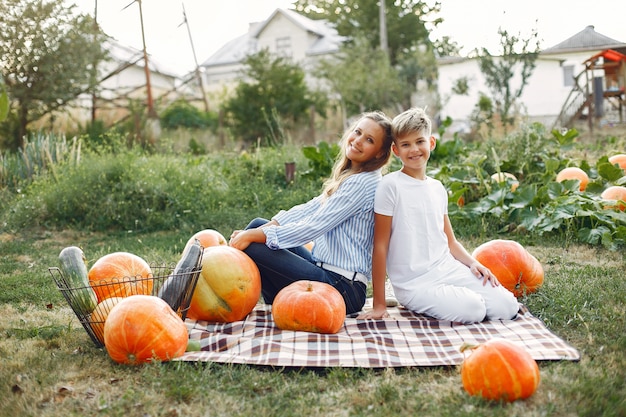 Mutter und Sohn, die auf einem Garten nahe vielen Kürbisen sitzen