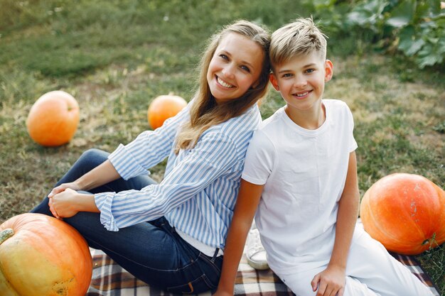 Mutter und Sohn, die auf einem Garten nahe vielen Kürbisen sitzen