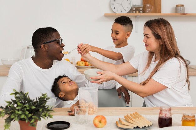 Mutter und Sohn füttern den Vater mit etwas zu essen