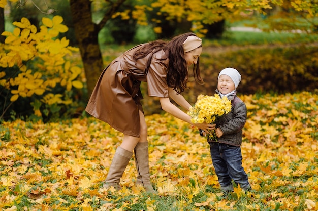 Mutter und Sohn gehen spazieren und haben gemeinsam Spaß im Herbstpark.