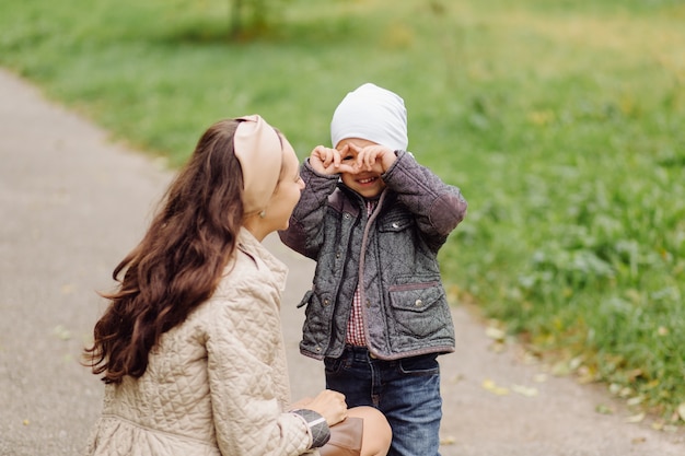 Kostenloses Foto mutter und sohn gehen spazieren und haben gemeinsam spaß im herbstpark.