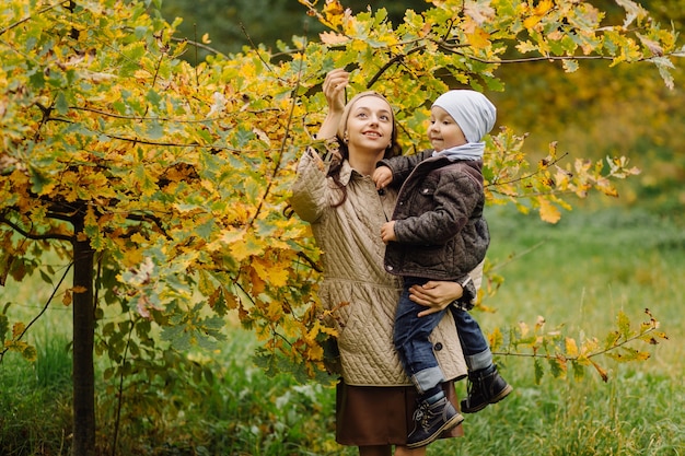 Mutter und Sohn gehen spazieren und haben gemeinsam Spaß im Herbstpark.