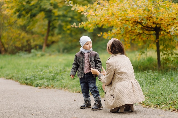 Mutter und Sohn gehen spazieren und haben gemeinsam Spaß im Herbstpark.