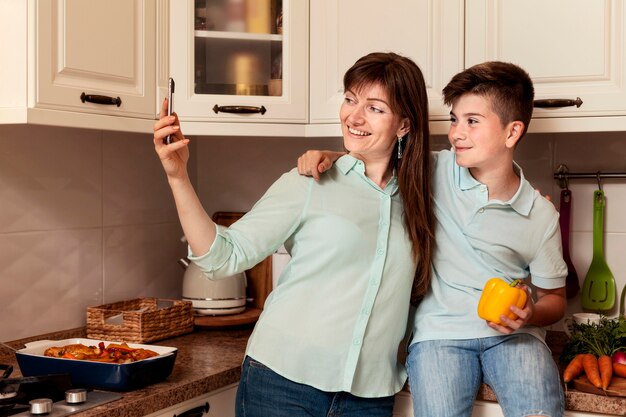 Mutter und Sohn nehmen Selfie zusammen mit Gemüse