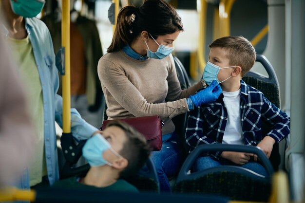 Mutter und Sohn reisen während der Coronavirus-Pandemie mit Vorsichtsmaßnahmen mit dem Bus