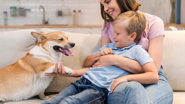 Mutter und Sohn spielen mit Corgi Hund