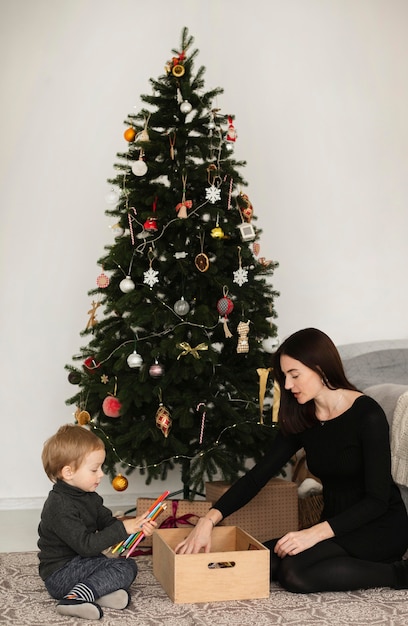 Mutter und Sohn spielen neben Weihnachtsbaum