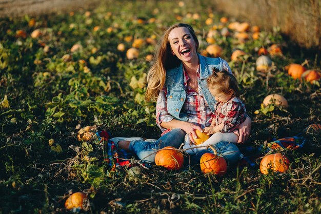 Mutter und Tochter auf einem Feld mit Kürbissen, Halloweenabend