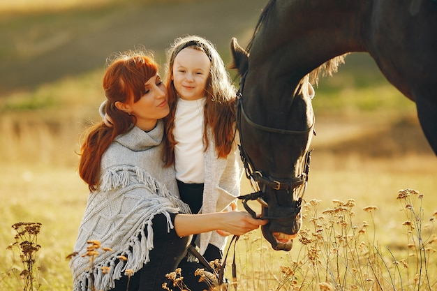 Mutter und Tochter auf einem Gebiet, das mit einem Pferd spielt