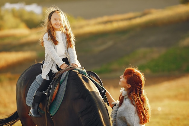 Mutter und Tochter auf einem Gebiet, das mit einem Pferd spielt