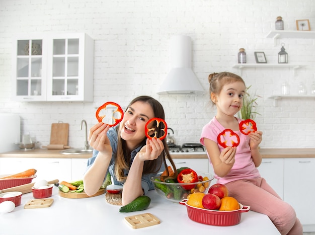 Mutter und Tochter bereiten in der Küche einen Salat zu. Viel Spaß und spielen Sie mit Gemüse.