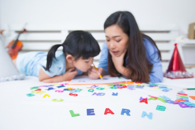 Mutter und Tochter, die das Alphabet studieren