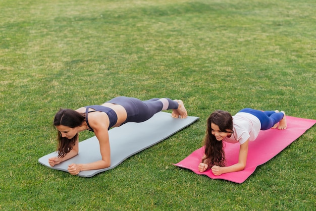 Mutter und Tochter, die draußen planking sind