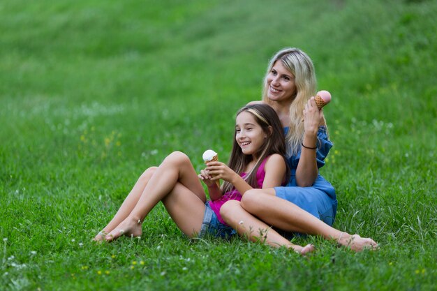 Mutter und Tochter, die im Gras mit Eiscreme liegen