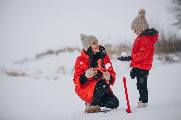 Mutter und Tochter, die im Winterpark spielen