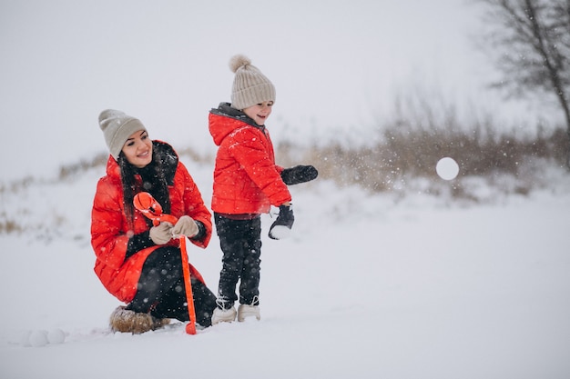 Mutter und Tochter, die im Winterpark spielen