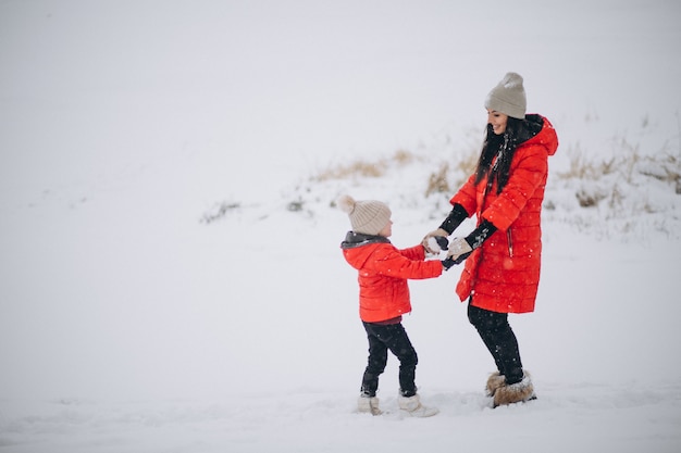 Mutter und Tochter, die im Winterpark spielen