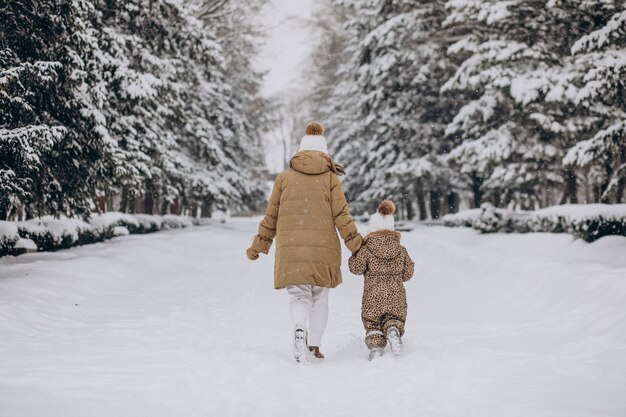Mutter und Tochter haben Spaß im Park voller Schnee