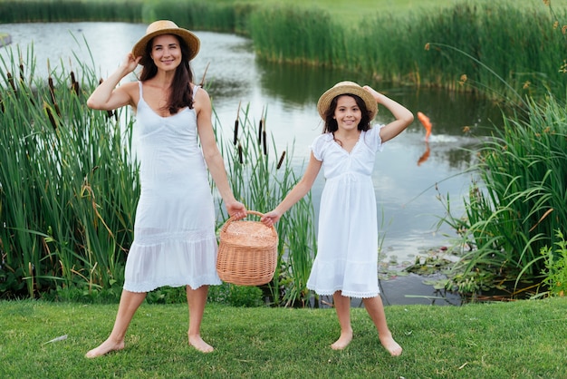 Mutter und tochter halten picknickkorb am see