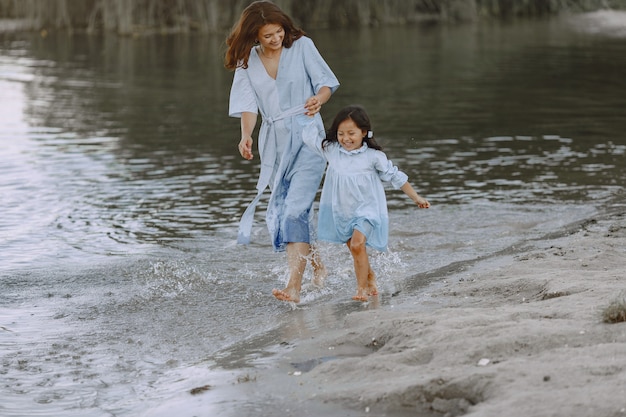 Mutter und Tochter in identischen Kleidern. Familie spielt am Fluss.