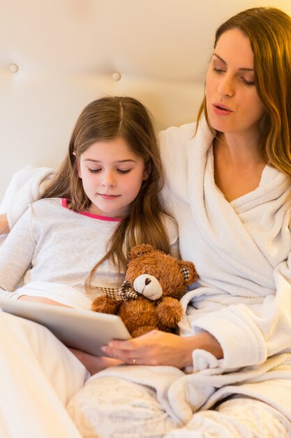 Mutter und Tochter mit der digitalen Tablette im Schlafzimmer