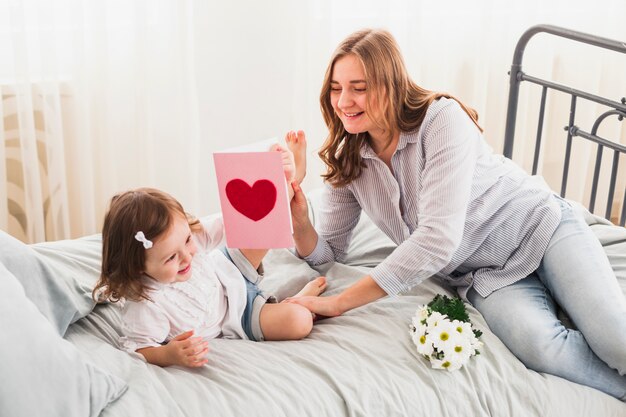 Mutter und Tochter mit der Grußkarte, die Spaß hat