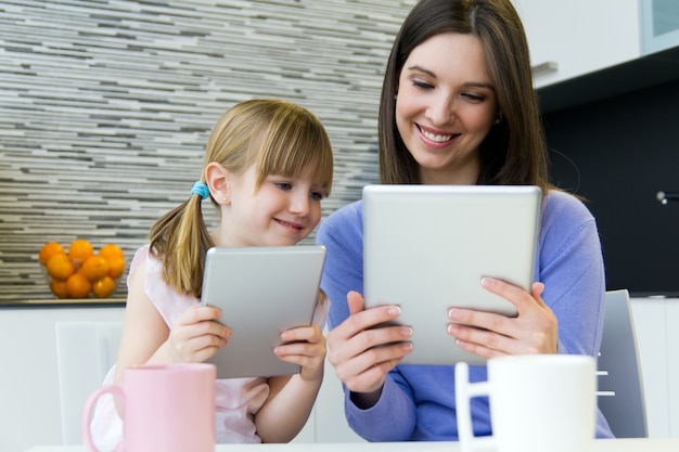 Mutter und Tochter mit einer digitalen Tablette in der Küche