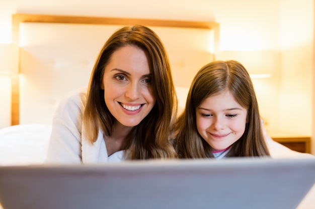 Mutter und Tochter mit Laptop im Schlafzimmer