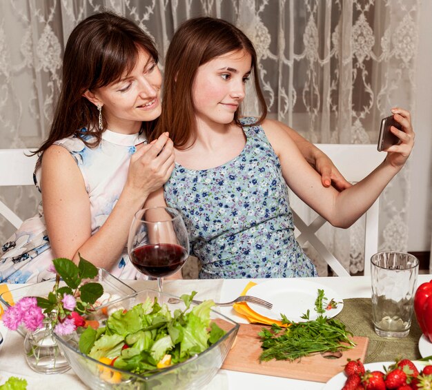 Mutter und Tochter nehmen Selfie am Esstisch