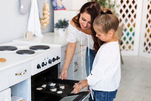 Mutter und Tochter setzt Cookies Fach in Ofen