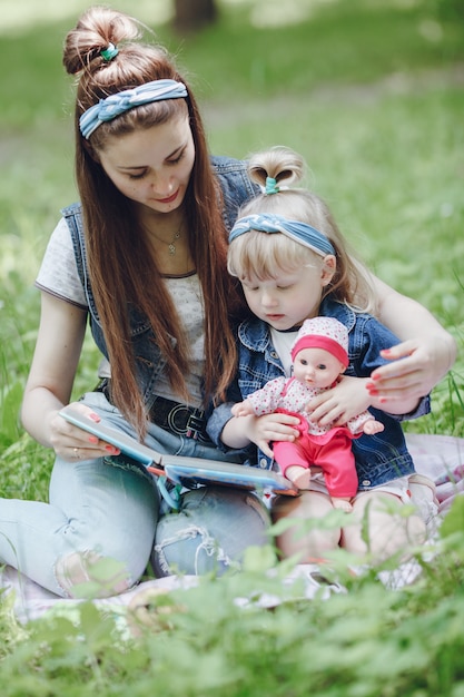 Mutter und Tochter sitzen auf dem Boden, ein Buch und das Mädchen mit einer Puppe zu lesen