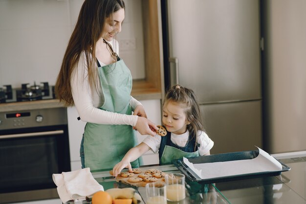 Mutter und Tochter sitzen in einer Küche mit Keksen