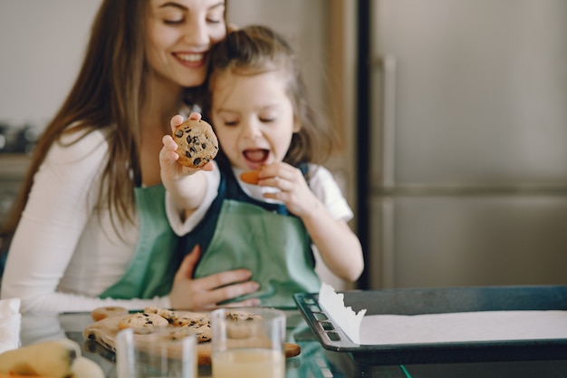 Mutter und Tochter sitzen in einer Küche mit Keksen