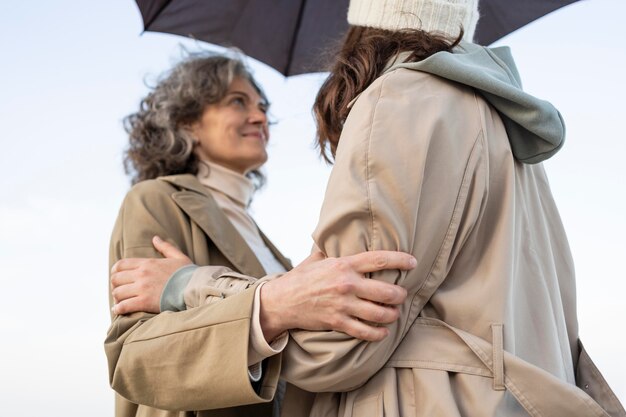 Mutter und Tochter teilen einen zärtlichen Moment am Strand unter einem Regenschirm