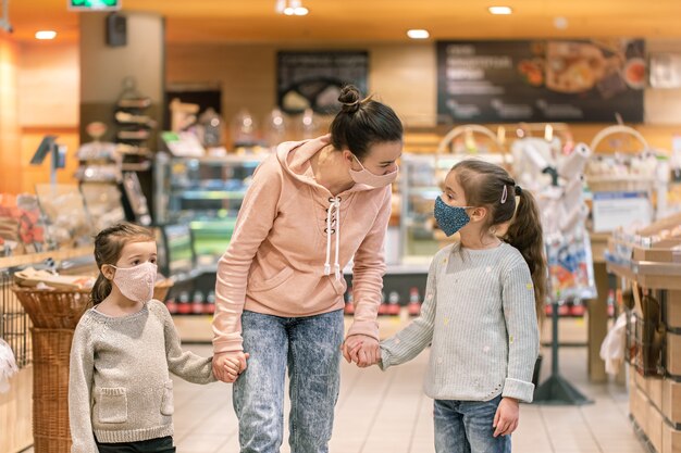 Mutter und Töchter kaufen während der Quarantäne aufgrund der Coronavirus-Pandemie in Masken im Laden ein.