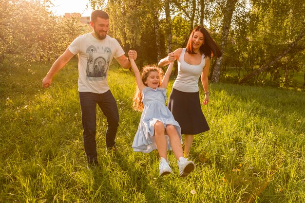 Mutter und Vater schwingen ihre Tochter zwischen ihnen