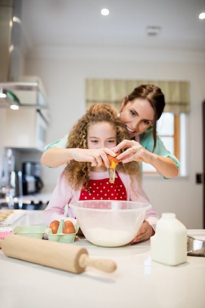Mutter Unterstützung Tochter in Eier in der Küche zu brechen